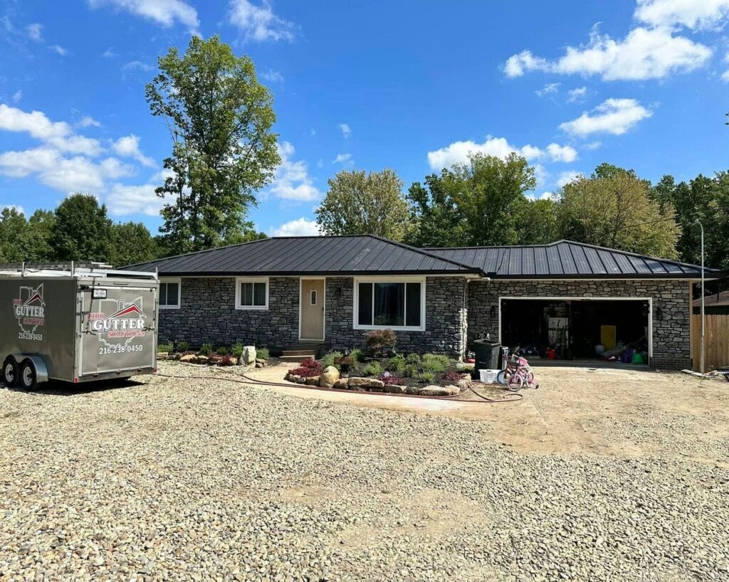 Stone house with a metal roof and a trailer from Ohio Gutter Solutions, showcasing services by the best gutter company in Cleveland.